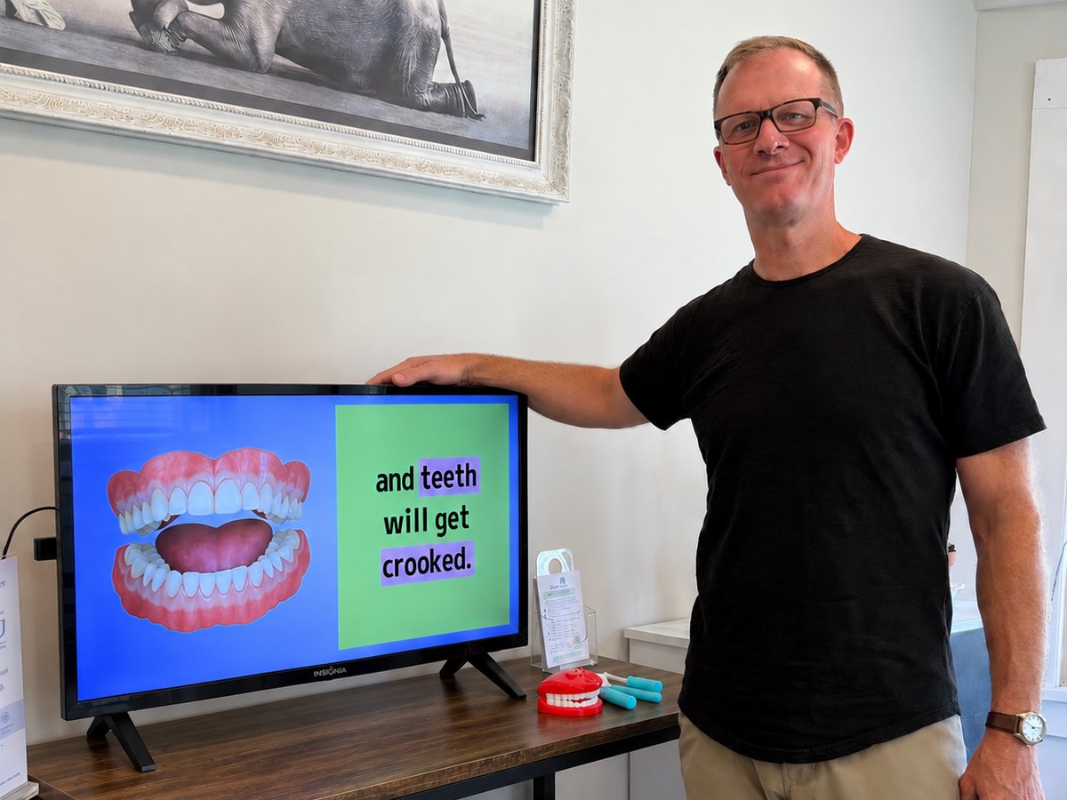 Dr. Eric Christensen beside a TV playing Channel D at Westhampton Dental